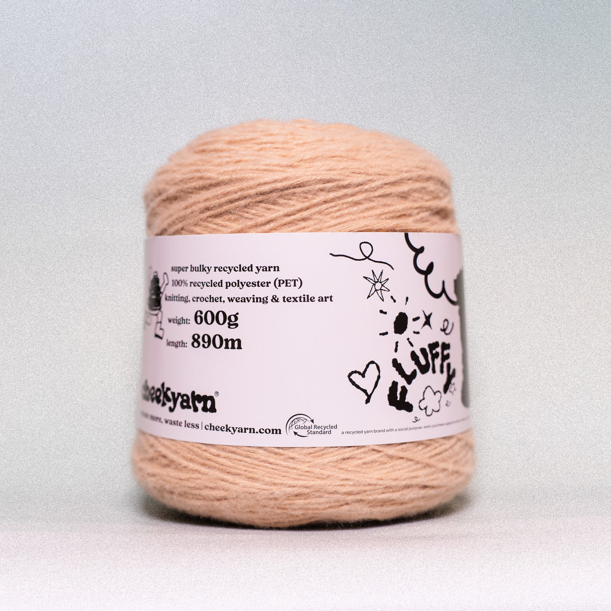A single spool of peach-colored fluffy recycled yarn with a white paper label, photographed against a neutral light gray background.