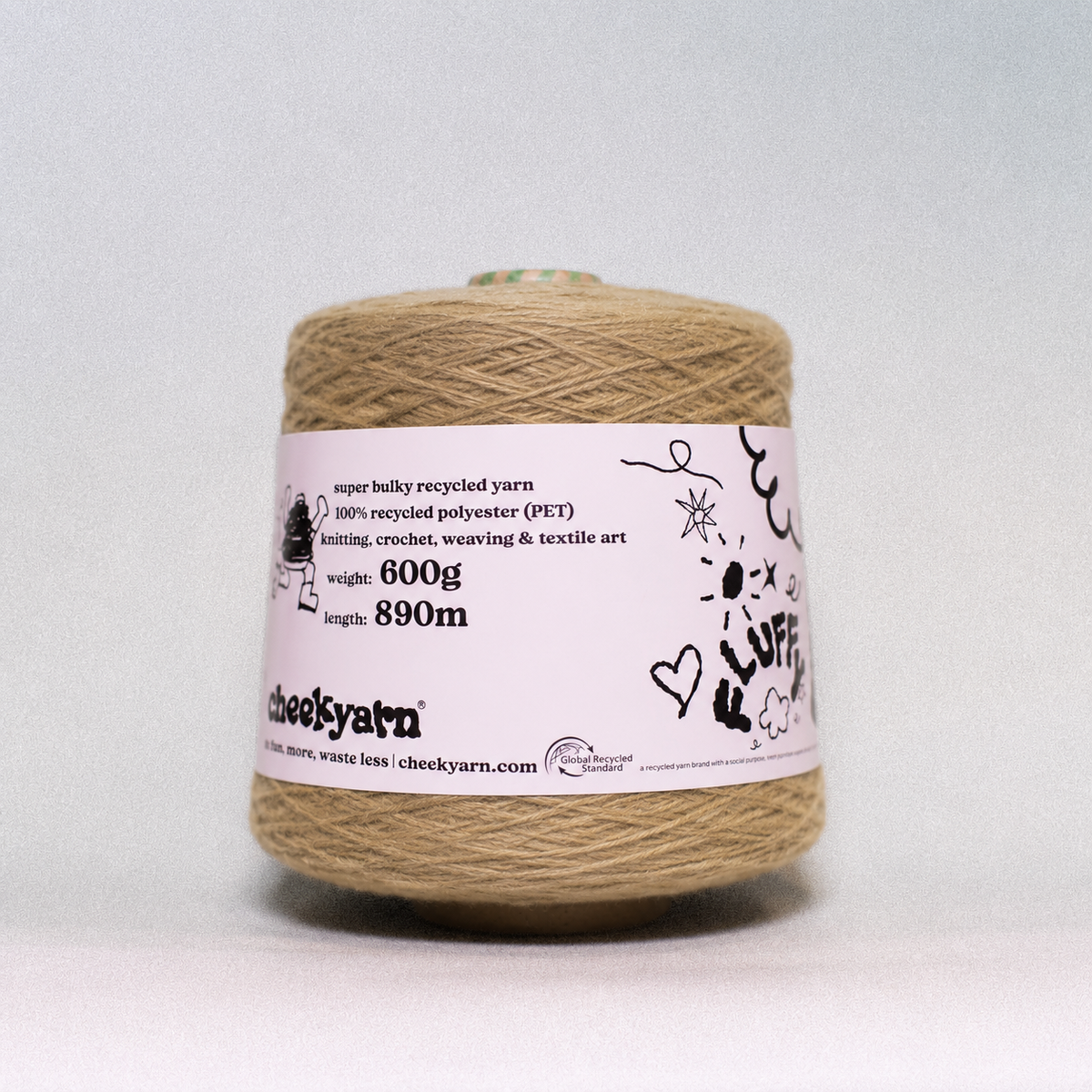 A spool of Cheeky Yarn recycled PET yarn in a natural tan color, wrapped with a white paper label showing product details, on a light gray background.