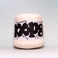 A ball of pale peach-colored yarn with a white paper label wrapped around it, featuring bold black graffiti-style lettering that reads 'COOPS'. The background is a clean, neutral light gray studio backdrop.