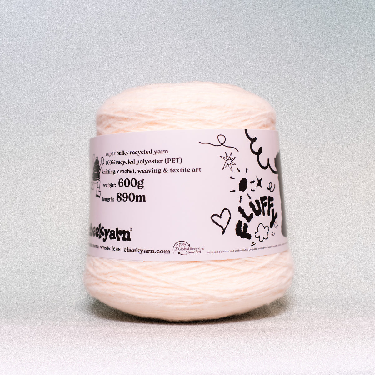 A ball of pale peach-colored recycled polyester yarn with a white paper label, photographed against a neutral light gray background.