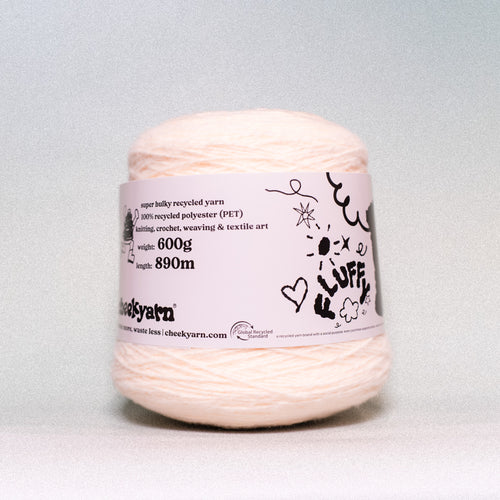 A ball of pale peach-colored recycled polyester yarn with a white paper label, photographed against a neutral light gray background.