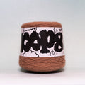 A ball of brown yarn wrapped in a white paper label with bold black text and doodles, photographed against a light gray background.