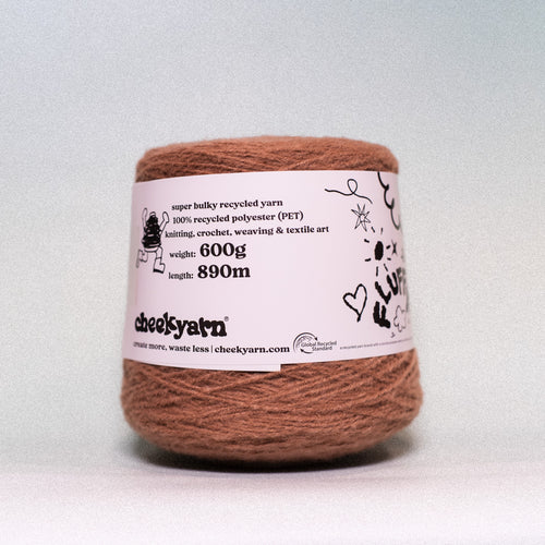 A single spool of brown recycled polyester yarn with a white paper label, photographed against a neutral light gray background.