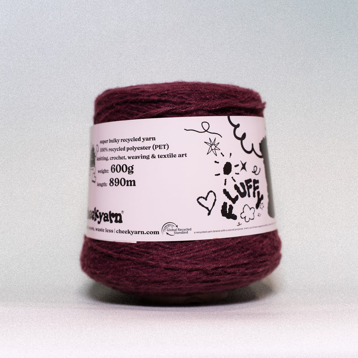 A ball of chunky recycled yarn in a deep burgundy color, wrapped with a white paper label that reads 'chuck yarn' and features hand-drawn black doodles, set against a plain light gray background.