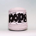 A ball of light pink yarn with a white paper label featuring bold black graffiti-style lettering, photographed against a neutral light gray background.