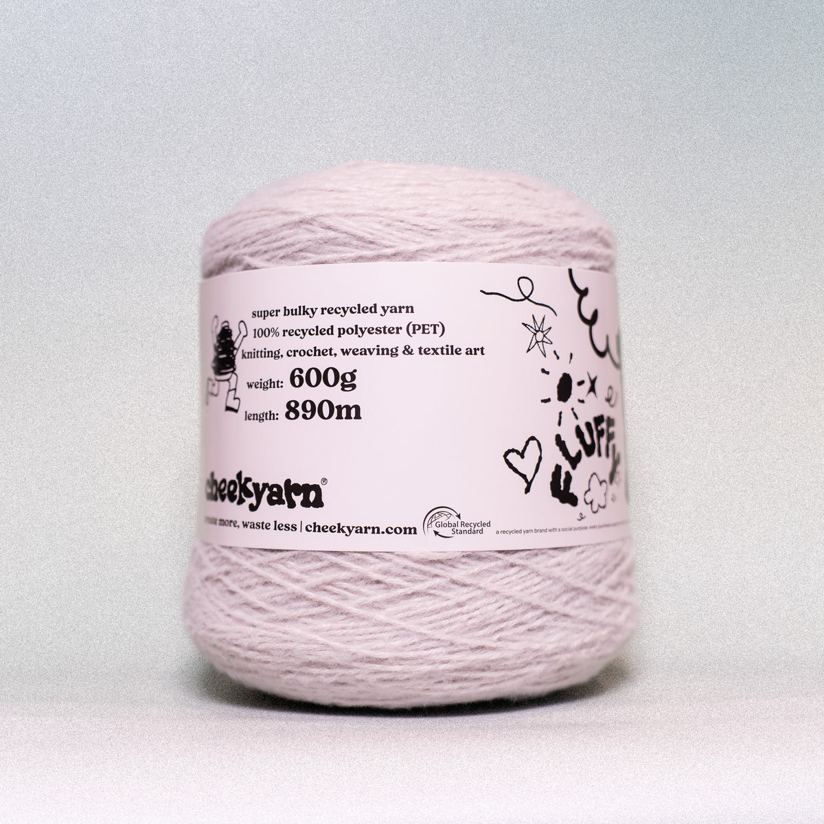A single ball of light pink recycled yarn with a white paper label, photographed against a neutral light gray background.