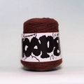 A ball of dark brown yarn wrapped in a white paper label with black graphic text, photographed against a neutral light gray background.