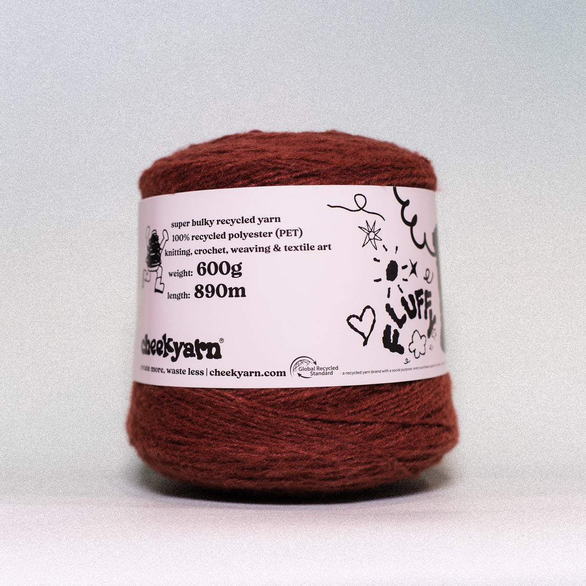 A single skein of chunky recycled yarn in a rust-brown color, wrapped with a white paper label that reads 'cheekyarn' and shows product details, photographed against a neutral light gray background.